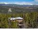 A brick home sits nestled among lush evergreen trees with stunning views of snow-capped mountains at 401 Highway 72, Golden, CO 80403