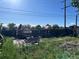 Backyard with overgrown foliage, a damaged fence, and a distant view of a playground at 841 S 6Th Ave, Brighton, CO 80601