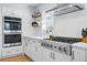 Modern kitchen with a built-in oven and a stainless steel gas range, and custom wood shelves at 6787 E Exposition Ave, Denver, CO 80224