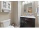 This bathroom features a toilet, sink with granite counters, dark wood cabinetry, and a white medicine cabinet at 3358 Castle Butte Dr, Castle Rock, CO 80109