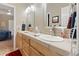 This bathroom has double sinks with a tile counter, wood cabinets, and a large mirror at 3358 Castle Butte Dr, Castle Rock, CO 80109