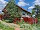 Fenced backyard with mature trees and colorful flower garden at 347 Buena Vista Ave, Palmer Lake, CO 80133