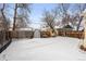 Snow covered backyard with wooden fence and a small greenhouse at 4151 Zenobia St, Denver, CO 80212