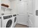 Functional laundry room with modern washer and dryer, white walls, and shelving for storage at 4569 Copeland Loop # 203, Highlands Ranch, CO 80126