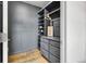 Spacious walk-in closet with custom shelving, drawers, and stylish gray walls and wood floor at 4569 Copeland Loop # 203, Highlands Ranch, CO 80126