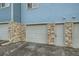 Garage and front door with stone accents on a blue townhome at 12032 Monaco St, Brighton, CO 80602