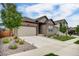 Street view of a charming home featuring a well-manicured lawn, a two-car garage, and stone accents at 5771 Slate River Pl, Brighton, CO 80601
