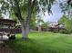 Expansive backyard with mature trees, green grass, and a covered patio at 18908 E Napa Dr, Aurora, CO 80013