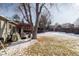 Snowy backyard with a wooden pergola, green grass peeking through the snow, and a mature tree at 18908 E Napa Dr, Aurora, CO 80013