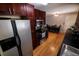 A well-lit kitchen featuring dark wood cabinetry, stainless steel appliances, and hardwood floors that transition into a dining area at 18908 E Napa Dr, Aurora, CO 80013