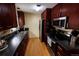 A kitchen featuring dark wood cabinetry, stainless steel appliances, and hardwood floors with black countertops at 18908 E Napa Dr, Aurora, CO 80013