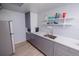 A functional kitchenette with gray cabinets, modern appliances, and convenient open shelving for storage at 18908 E Napa Dr, Aurora, CO 80013