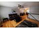 A spacious living room featuring hardwood floors, a ceiling fan, a dark leather sofa, and an adjacent dining area at 18908 E Napa Dr, Aurora, CO 80013