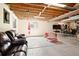 Unfinished basement with concrete floors, exposed rafters, and large leather seating area at 17601 E Eastman Pl, Aurora, CO 80013