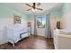 Bedroom with a ceiling fan, hardwood floors, a crib, and a dresser and changing table at 17601 E Eastman Pl, Aurora, CO 80013