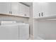 Bright laundry room features white washer and dryer with storage cabinets and hanging rack for convenience at 9768 E 62Nd Dr, Denver, CO 80238