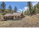 Rear view of the rustic cabin, surrounded by trees and natural landscape at 30570 Highway 72, Golden, CO 80403
