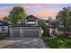 Charming two-story home featuring a three-car garage, manicured lawn, and lovely landscaping at sunset at 16342 Parkside Dr, Parker, CO 80134