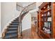 Grand foyer with a curved staircase, hardwood floors, wrought iron railing, and a built-in bookshelf at 16342 Parkside Dr, Parker, CO 80134