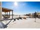 Snowy backyard with pergola, distant homes, and open space views at 11821 Joplin Ct, Commerce City, CO 80022