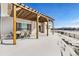 Covered patio with pergola, table and chairs, snowy yard, and distant views at 11821 Joplin Ct, Commerce City, CO 80022