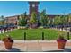 A green lawn in a town center square anchored by a clock tower with shops in the background at 1044 Rockhurst Dr # 202, Highlands Ranch, CO 80129