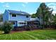 Large backyard featuring a wooden deck, green grass, mature trees, and solar panels on the roof at 4753 S Gar Way, Littleton, CO 80123