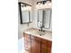 Bathroom vanity featuring wood cabinets, a sink, black hardware, and a modern light fixture with two mirrors at 4753 S Gar Way, Littleton, CO 80123