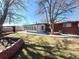 Large backyard featuring brick planter, sun room addition, and mature trees at 6556 Wolff St, Arvada, CO 80003