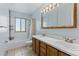 Well-lit bathroom with a double sink vanity, neutral tile flooring, and a shower-tub combination, offering functionality at 4581 S Garrison St, Littleton, CO 80123