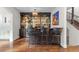 Stylish bar area features dark cabinetry, glass shelving, and seating for three at 579 Madison St, Denver, CO 80206