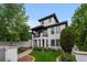 Elegant white home with tile roof, black trim, arched porch, balcony and professionally landscaped lawn at 579 Madison St, Denver, CO 80206