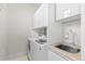 Bright laundry room featuring modern, front-loading washer and dryer, sink, and storage cabinets at 579 Madison St, Denver, CO 80206