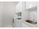 White laundry room with built in storage cabinets, sink, and front loading machines at 579 Madison St, Denver, CO 80206
