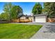 This backyard features a lawn, a wooden deck, a brick house, and a gravel driveway at 7120 S Sheridan Ct, Littleton, CO 80128