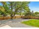 Fenced backyard featuring a gravel area and small grass section, with mature trees overhead at 7120 S Sheridan Ct, Littleton, CO 80128