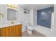 Well-lit bathroom with a wooden vanity, blue tiled shower/tub, and neutral hexagonal tile floors at 7120 S Sheridan Ct, Littleton, CO 80128