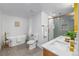 Modern bathroom with dual sinks, glass-enclosed shower, soaking tub, and stylish gold fixtures at 7120 S Sheridan Ct, Littleton, CO 80128