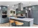 Modern kitchen with stainless steel appliances, island with cooktop, gray cabinets, and designer backsplash at 7120 S Sheridan Ct, Littleton, CO 80128