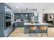 Bright eat-in kitchen boasts gray cabinets, stainless appliances, an island with counter seating, and pendant lighting at 7120 S Sheridan Ct, Littleton, CO 80128