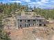 Aerial view of a sprawling home on a hillside, surrounded by lush greenery and a blue sky at 13288 Elsie Rd, Conifer, CO 80433