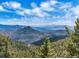 Expansive mountain vista with snow-capped peaks and evergreen forests under a blue sky with scattered clouds at 13288 Elsie Rd, Conifer, CO 80433