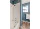 Bright bathroom with a white tiled shower, a window providing natural light and blue walls at 5292 W Fair Dr, Littleton, CO 80123