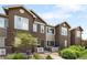Charming townhome with brick accents, a quaint entryway, and lush green landscaping at 15546 W 64Th Loop # C, Arvada, CO 80007