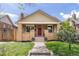 Charming brick bungalow featuring a classic front porch, red door, and well-manicured lawn at 3649 N Garfield St, Denver, CO 80205