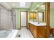 Bathroom features tiled shower, soaking tub, skylight, double sinks, and wood cabinets at 12414 Clayton Way, Thornton, CO 80241