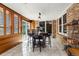 Sunroom dining area with tile floors, brick walls, and lots of windows at 12414 Clayton Way, Thornton, CO 80241