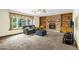 Cozy living room with carpet, a brick fireplace, built-in bookshelves, and large windows at 12414 Clayton Way, Thornton, CO 80241