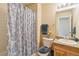 Cozy bathroom featuring a shower with patterned blue curtain, neutral tones, and a mirrored vanity at 12766 Jasmine St # D, Thornton, CO 80602