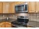 This kitchen is complete with wooden cabinets, a microwave, and sleek stainless steel appliances at 12766 Jasmine St # D, Thornton, CO 80602